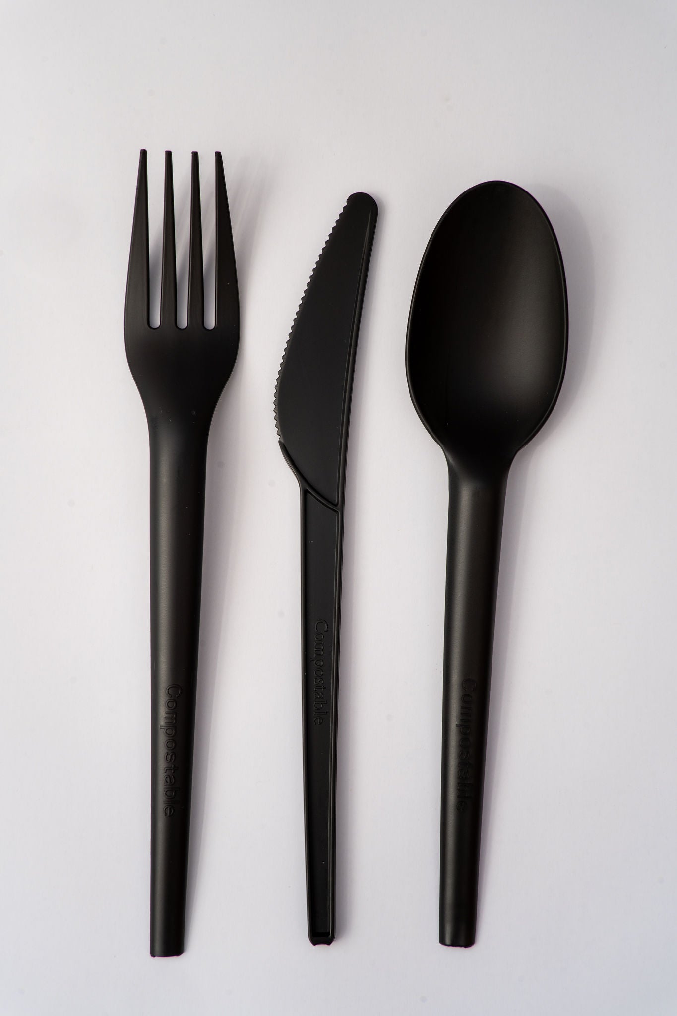 Black compostable PLQ fork, knife, and spoon set on a light gray background - Cyclups Plantastiq non-plastic tableware made from wheat