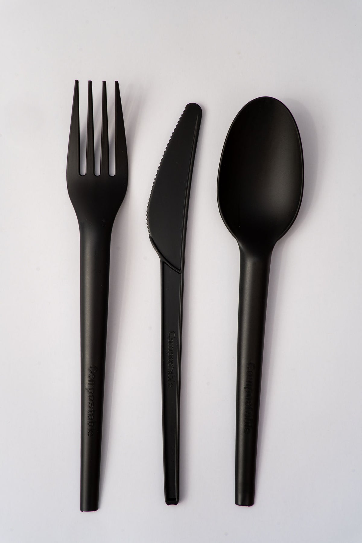 Black compostable PLQ fork, knife, and spoon set on a light gray background - Cyclups Plantastiq non-plastic tableware made from wheat